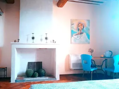 a living room with a fireplace and a table and chairs at Chambre d'hôtes face au lavoir in Méthamis