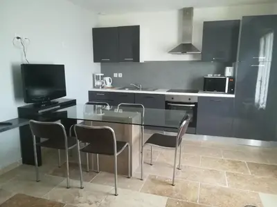 a kitchen with a glass table and chairs in it at Au pays du Ventoux in Le Thor