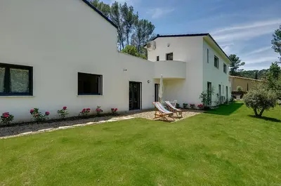 a white house with two chairs in a yard at Maison du Prignon in Saint-Marc-Jaumegarde