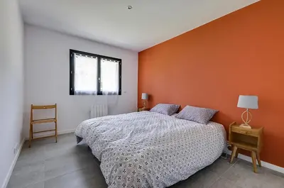 a bedroom with a bed and an orange wall at Maison du Prignon in Saint-Marc-Jaumegarde