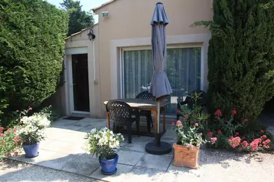 a patio with a table and an umbrella and some plants at Gite des Taillades in Les Taillades