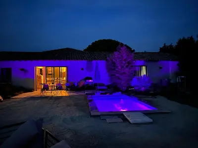 a swimming pool with purple lights in front of a house at Loft piscine et spa provence in LʼIsle-sur-la-Sorgue