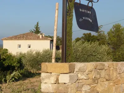 a stone wall with a sign in front of a building at Mas Bastide st Victor à 5 mn de Lourmarin in Puyvert