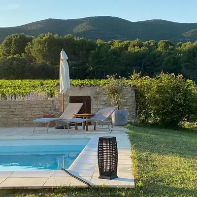 a pool with chairs and an umbrella and a table at Mas Bastide st Victor à 5 mn de Lourmarin in Puyvert