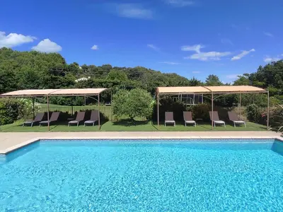 a swimming pool with chairs and umbrellas at Les Grandes Terres - Gîtes & SPA in Mérindol