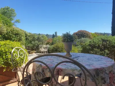 a table and chairs with a vase on a patio at La Parenthèse in Lauris