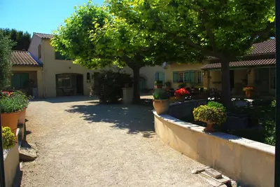 a house with trees and potted plants in a yard at Le Mas de l'Amandier in Saint-Saturnin-lès-Avignon
