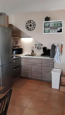 a kitchen with a refrigerator and a clock on the wall at Le Mas des Vergers in Salon-de-Provence