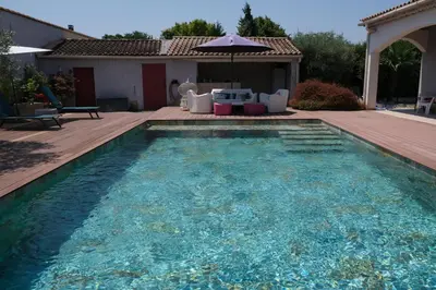 a swimming pool in a backyard with an umbrella at pleasant one-level villa with private pool in the thor village, close to l'isle sur la sorgue - 6 persons in Le Thor