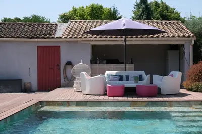 a patio with chairs and an umbrella next to a pool at pleasant one-level villa with private pool in the thor village, close to l'isle sur la sorgue - 6 persons in Le Thor
