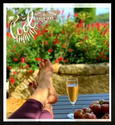 a person with their feet on a table with a glass of wine at La petite Galéjade in Gordes