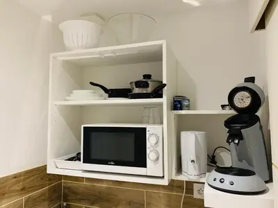 a microwave in a white cabinet with a clock at Cassis Studio in Aix-en-Provence