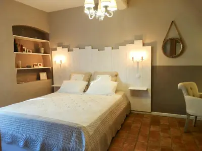 a bedroom with a bed and a chandelier at Un Patio en Luberon in Ansouis