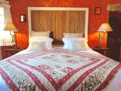 a bedroom with a bed with a red wall at Un Patio en Luberon in Ansouis