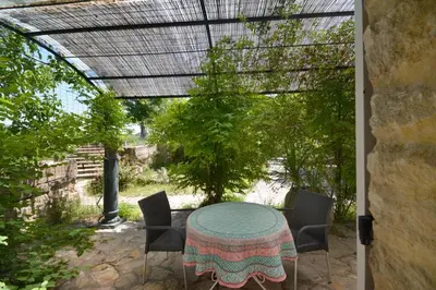 a table and chairs on a patio with a pergola at Moulin d'Antelon B&B in Crillon-le-Brave