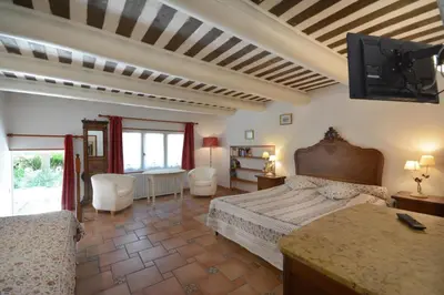 a bedroom with two beds and a tv on the wall at Moulin d'Antelon B&B in Crillon-le-Brave