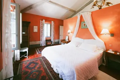 a bedroom with a white bed with an orange wall at Bastide Rose in Le Thor