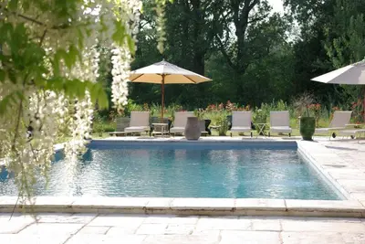 a swimming pool with chairs and umbrellas at Bastide Rose in Le Thor