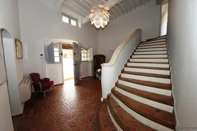a hallway with a staircase in a house with a chandelier at Domaine de l'Enclos in Gordes