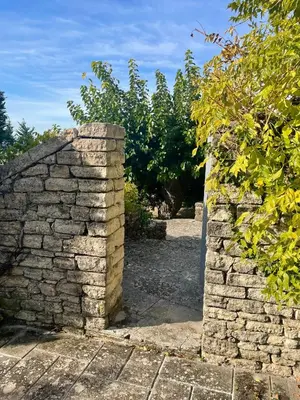 an entrance to a stone wall with trees in the background at Domaine de l'Enclos in Gordes