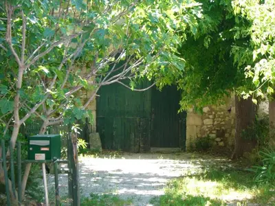 an entrance to a building with a gate and trees at Maison charmante avec terrasse et jardin à Noves in Noves