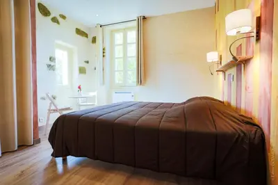 a bedroom with a bed with a brown blanket at Les Jardins de l'Abbaye in Simiane-la-Rotonde