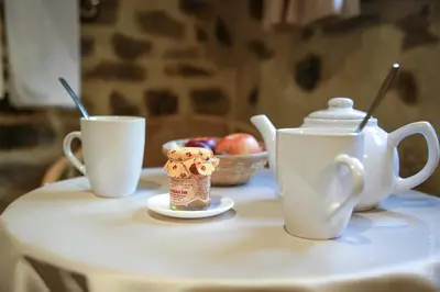 a table with two cups and a tea pot and a bowl of apples at Les Jardins de l'Abbaye in Simiane-la-Rotonde
