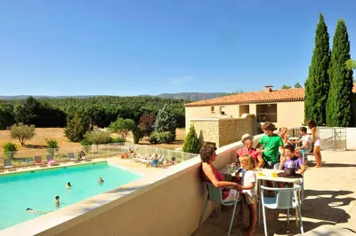 a group of people sitting at a table near a swimming pool at Résidence Goélia Le Domaine du Moulin Blanc in Gordes