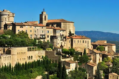 a group of buildings on a hill with trees at Résidence Goélia Le Domaine du Moulin Blanc in Gordes