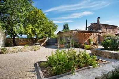 a garden in front of a house with a church at Domaine Les Petites Vaines in Goult