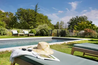 a hat and sunglasses sitting on a table next to a pool at Domaine Les Petites Vaines in Goult