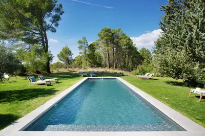 a swimming pool in the middle of a yard with benches at Domaine Les Petites Vaines in Goult