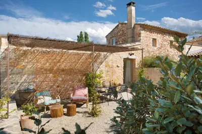 a stone building with a table and chairs in a yard at Domaine Les Petites Vaines in Goult