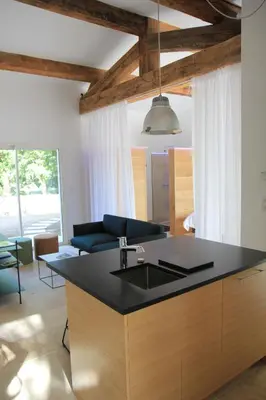 a kitchen with a sink and a living room at Le Fournil en Provence in Caseneuve