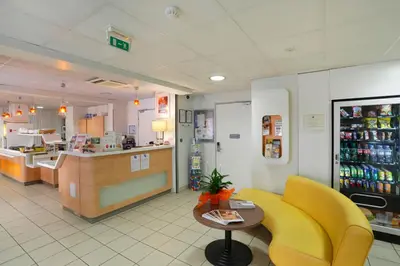 a fast food restaurant with a yellow chair and a counter at First Inn Hotel in Apt