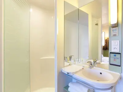 a bathroom with a sink and a shower with a mirror at First Inn Hotel in Apt