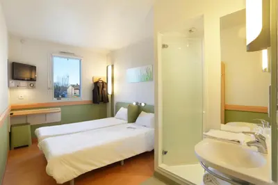 a hotel room with two beds and a sink at First Inn Hotel in Apt
