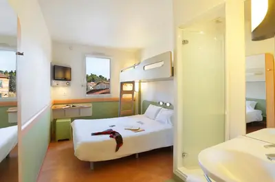 a hotel room with two beds and a mirror at First Inn Hotel in Apt