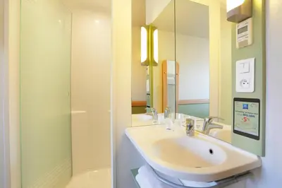 a white bathroom with a sink and a shower at First Inn Hotel in Apt