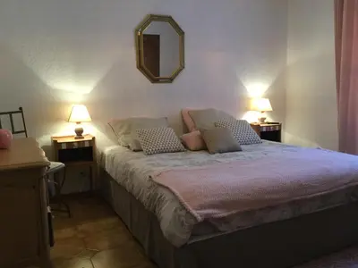 a bedroom with a bed with two lamps and a mirror at authentic provencal mas with pool, in the countryside of the village of sénas, close to the luberon and the alpilles, sleeps 8. in Sénas