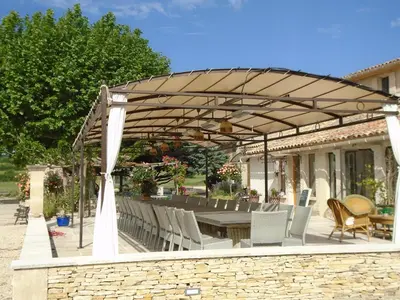 a patio with a table and chairs under a pergola at Chambres & Tables d'hôtes Moulin de Lavon in Gargas