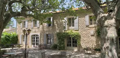 a stone building with tables and chairs in front of it at Hôtel Mas Valentine in Saint-Rémy-de-Provence