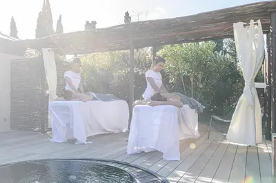 two women sitting on tables under a canopy at Hôtel Mas Valentine in Saint-Rémy-de-Provence