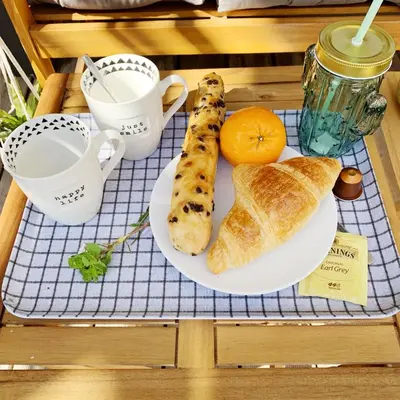 a breakfast tray with a plate of bread and an orange at Appart Hôtel Cézanne in Aix-en-Provence