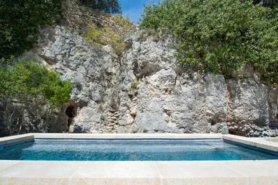 a swimming pool in front of a rock wall at La Ressence Luberon in Bonnieux