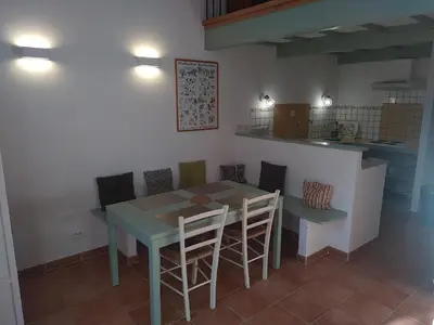 a dining room with a table and chairs and a kitchen at AU PIED DU VENTOUX in Flassan