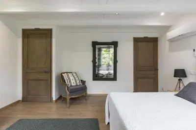 a bedroom with a bed and a chair and a mirror at Petite Maison du Ventoux in Mormoiron