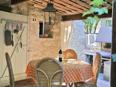 a dining room with a table and chairs and a stone wall at Splendid Villa in Viens with Swimming Pool in Viens
