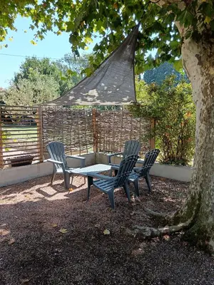 a table and chairs sitting under a tree at Gîte des deux platanes in Orgon