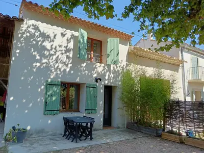 a white house with green shutters and a table at Gîte des deux platanes in Orgon